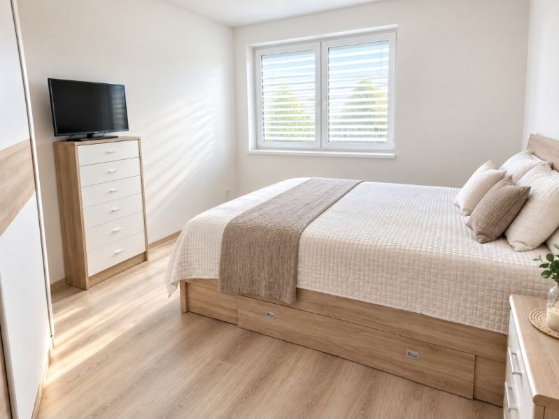 Bright bedroom with a bed, cabinet, and wood-decor flooring in a family house.