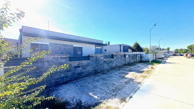 A family house in Horné Saliby with a concrete fence on a sunny street.