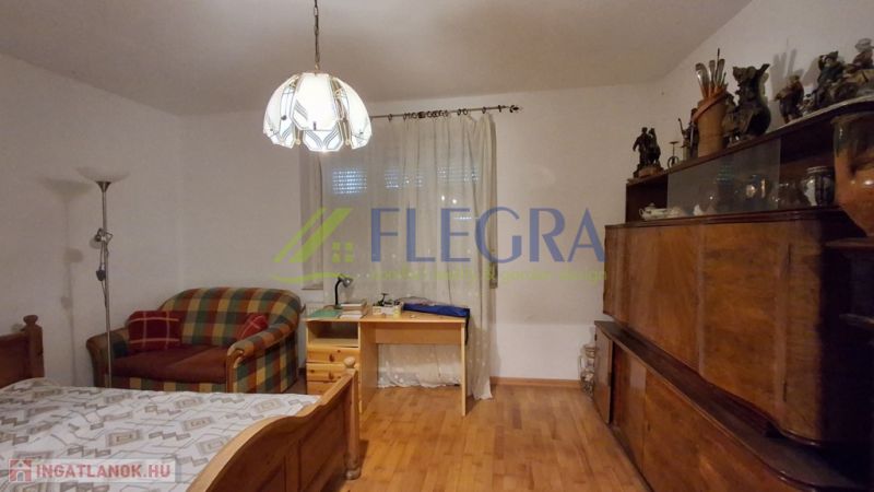 A room in a family house with a single bed and a wooden decor floor.