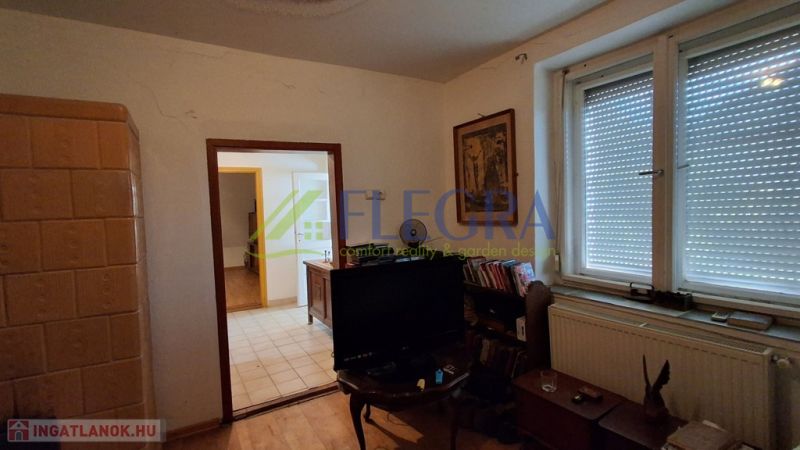 Room with a television, radiator, and tiled stove in a family house.