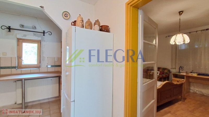 A kitchen in a family house with a refrigerator, brick decor, and wooden furniture.