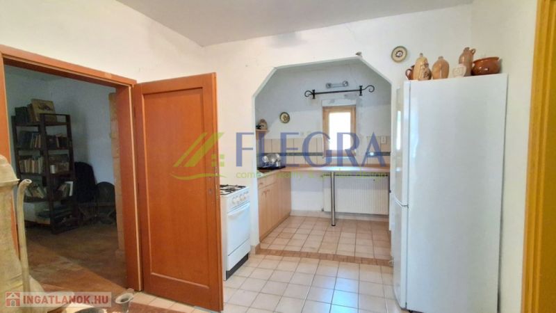 A kitchen in a family house with a ceramic floor, a gas stove, and a white refrigerator.