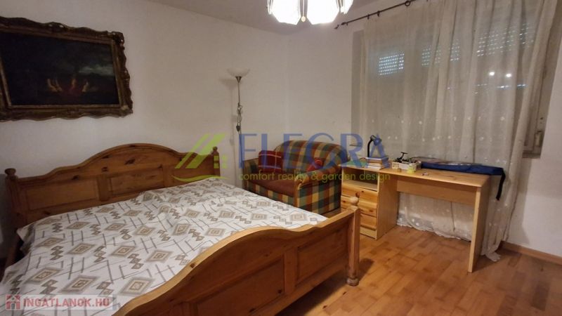 Bedroom in a family house with wooden decor, a bed, and a desk.