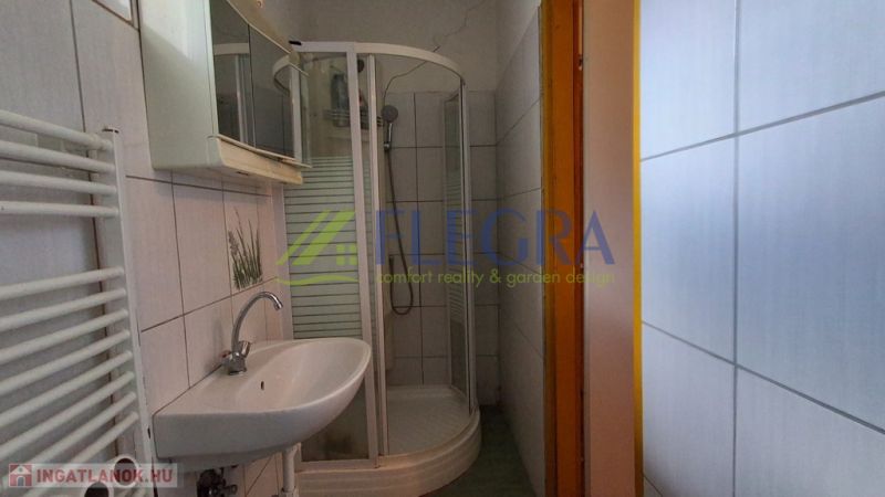 A bathroom in a family house with white tiles and a shower corner.
