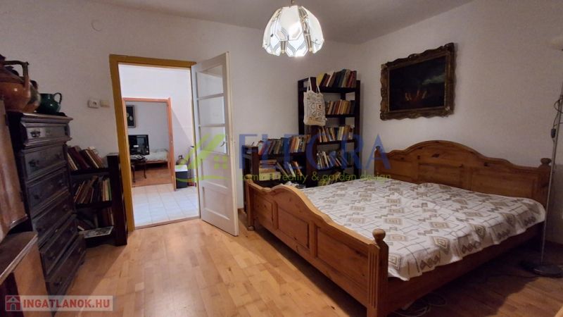 A bedroom in a family house with a wooden decor floor, a large bed, and a lamp.