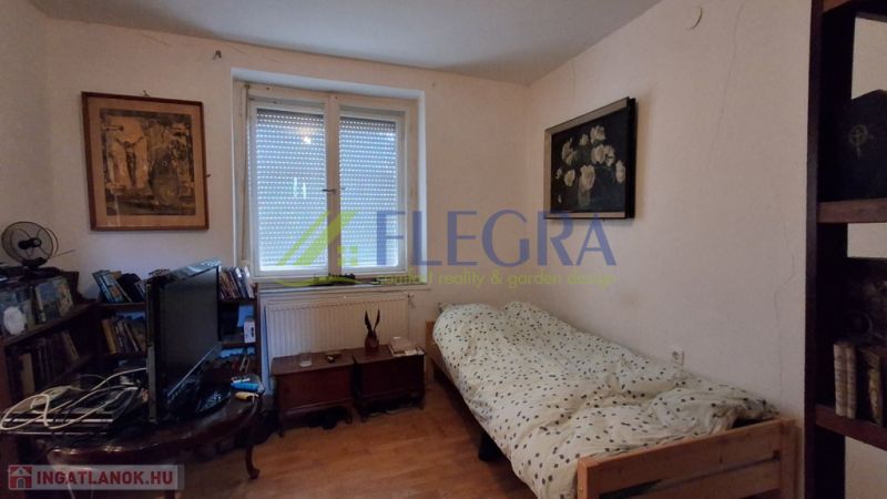 A room in a family house with a bed, a television, and a wooden decor floor.
