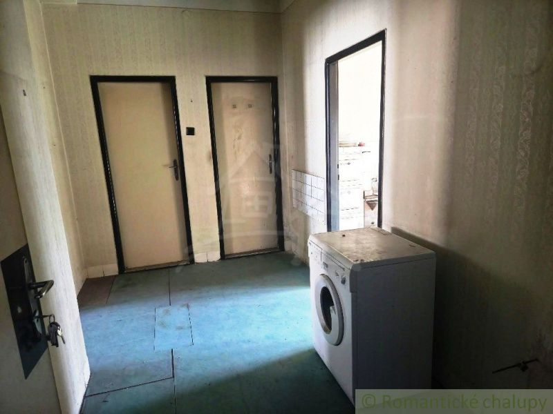 An interior with a washing machine, doors, and wallpapered walls in commercial premises.