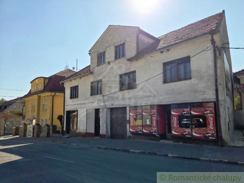 A building with commercial spaces in the town of Modrý Kameň, visible across the street.