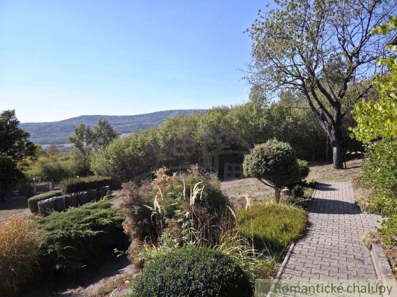 A cottage in Modrý Kameň with a landscaped garden and a view of the hilly countryside.