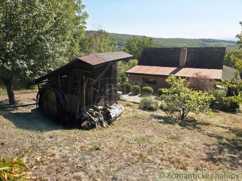A garden cottage in Modrý Kameň with a wooden shelter among trees and shrubs.