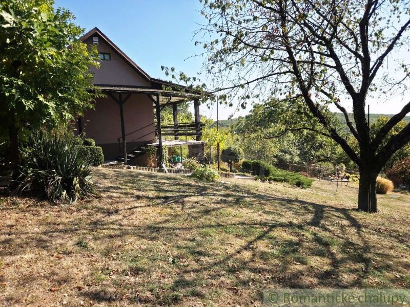 A cottage in Modrý Kameň, surrounded by greenery and trees in a beautiful rural setting.