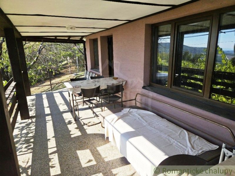 A covered terrace at the cottage in Modrý Kameň with seating and a view of nature.