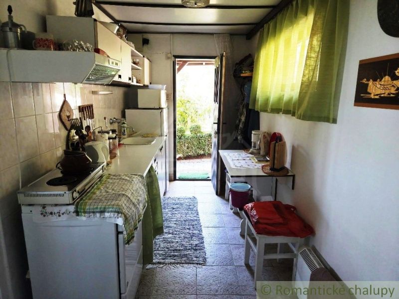 A kitchen in a cottage with traditional equipment, a cozy atmosphere, and a view of the garden.