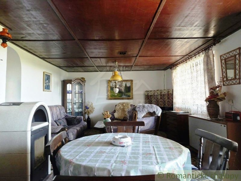 The interior of a cabin with a wooden decor floor, wooden ceiling, table, and fireplace.