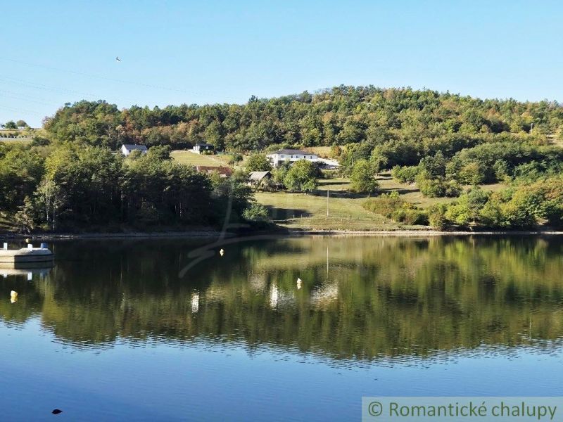 A view of a pond with trees and hills in the Gardens in Krupina.