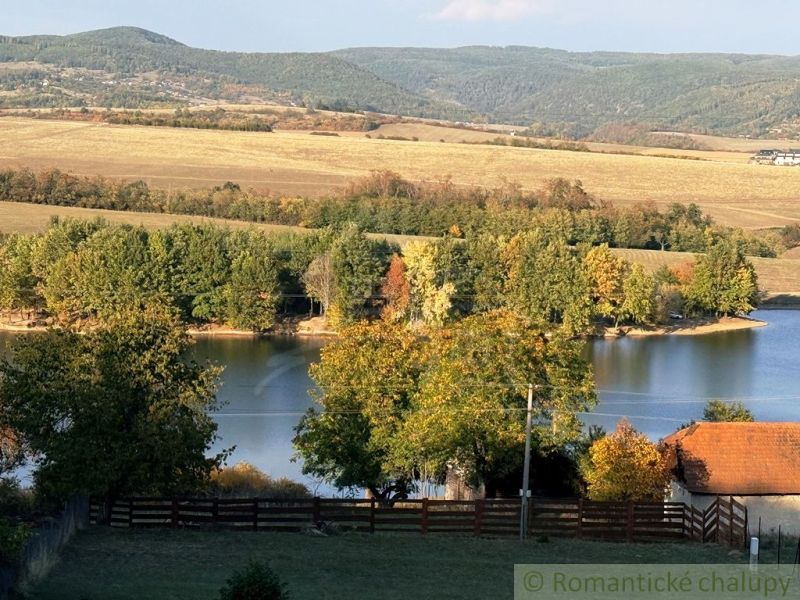 A lake surrounded by autumn trees and hills in the gardens in Krupina.