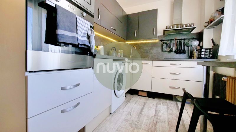 A kitchen with white and gray cabinets in a 2-room apartment, floor with wood decor.