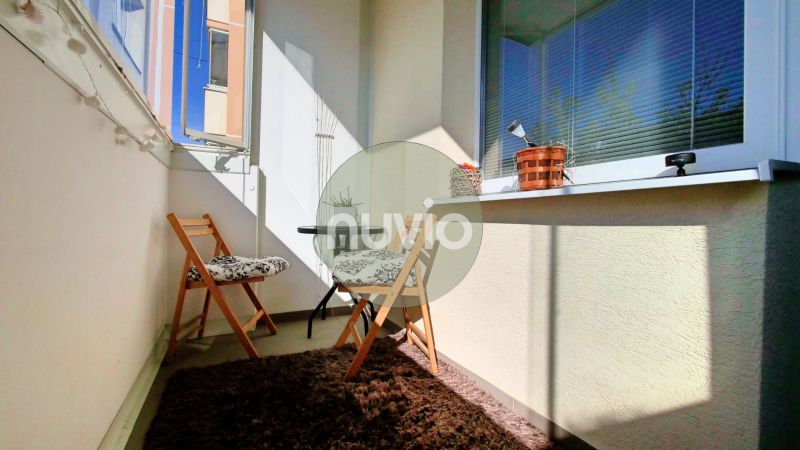 A balcony with two folding chairs and a carpet in a 2-room apartment.