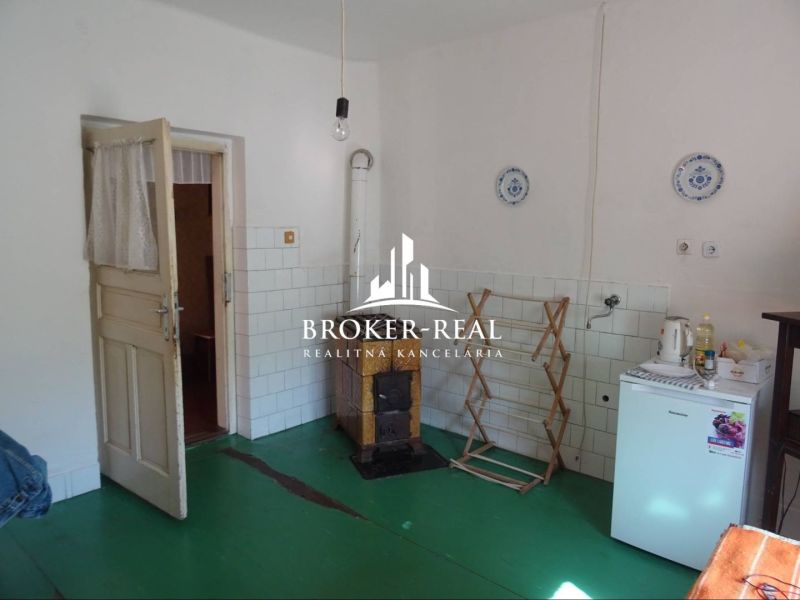 A room in a family house, simple furnishings, stove, green floor, light wall.