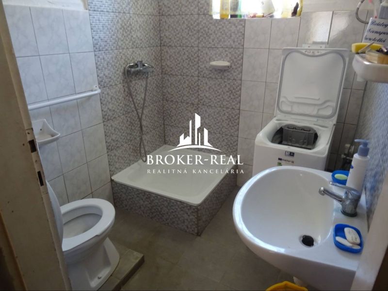 Bathroom in a family house with a shower, toilet, and washing machine.