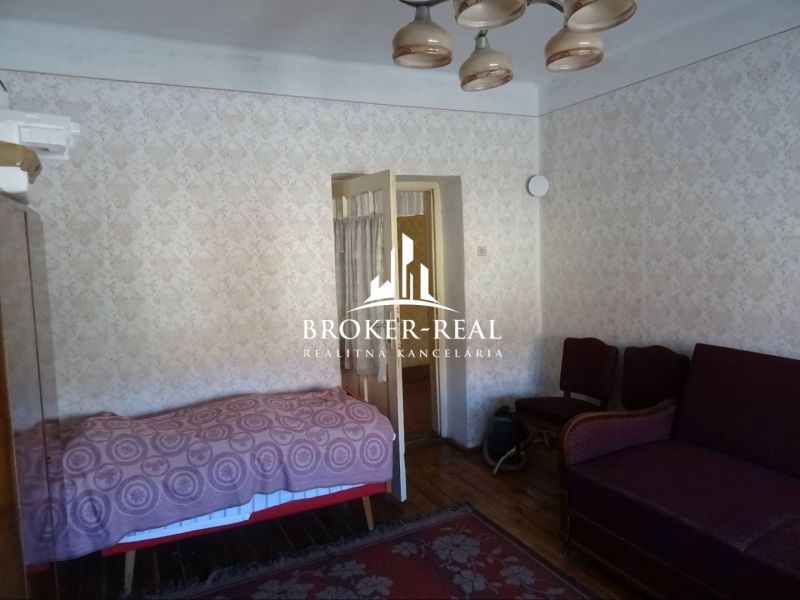 A room with a sofa, bed, and wooden decor flooring in a family house.