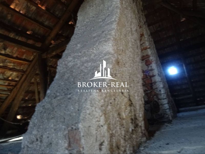The attic of a family house with a wooden structure and an old brick wall.